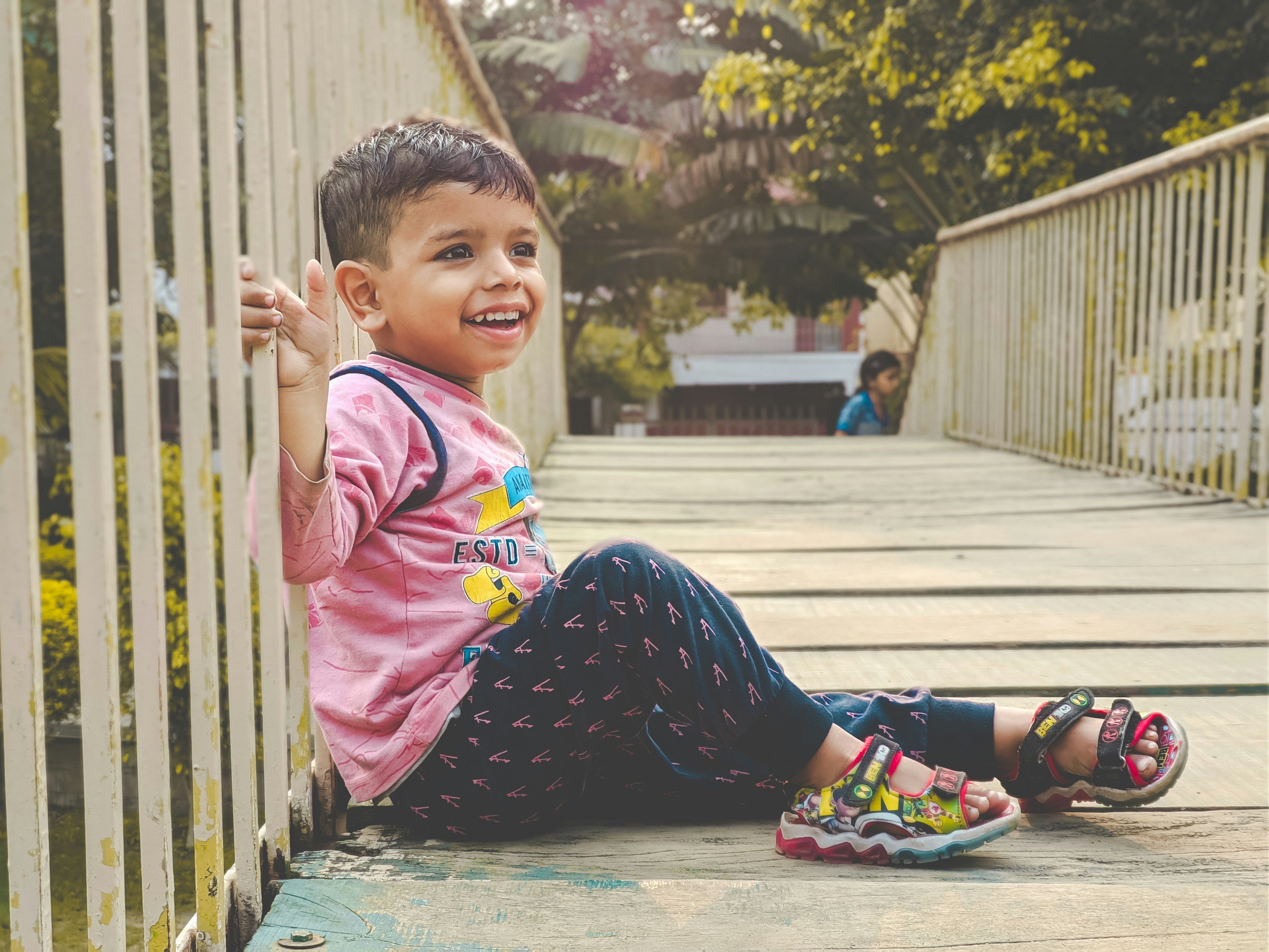 Happy child sitting on a bridge